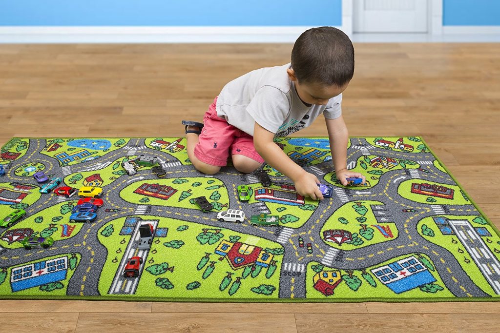 در این تصویر پسربچه‌ای را می‌بینیم که در حال بازی روی فرش ماشینی اتاق کودک است. فرش این پسربچه از نوع فرش بازی است. این فرش‌ها خلاقیت کودکان را افزایش می‌دهند. 